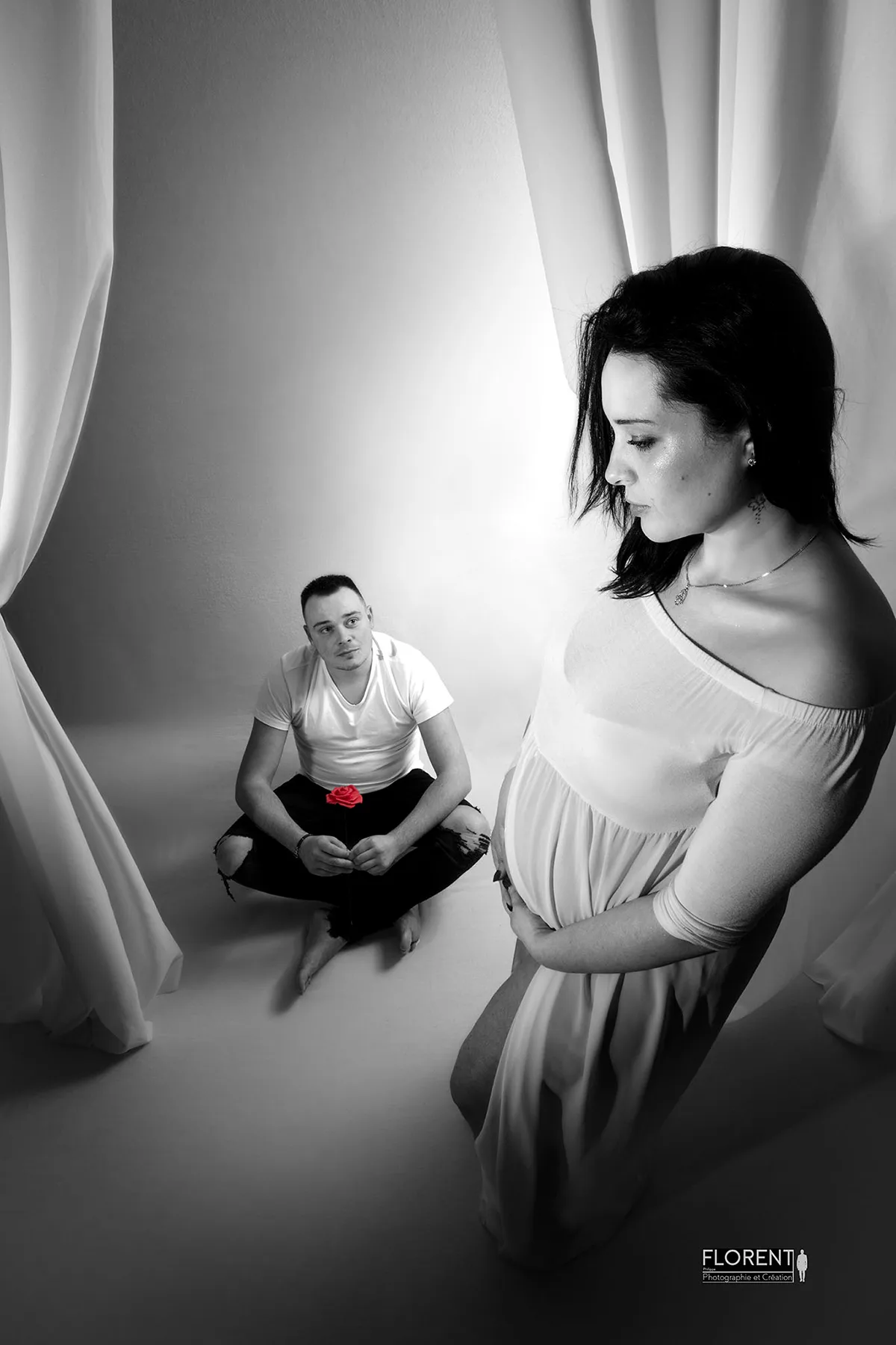 photographe maternité grossesse en noir et blanc scene papa assis rose rouge maman pensive florent photographe boulogne sur mer lille le touquet paris calais amiens berck